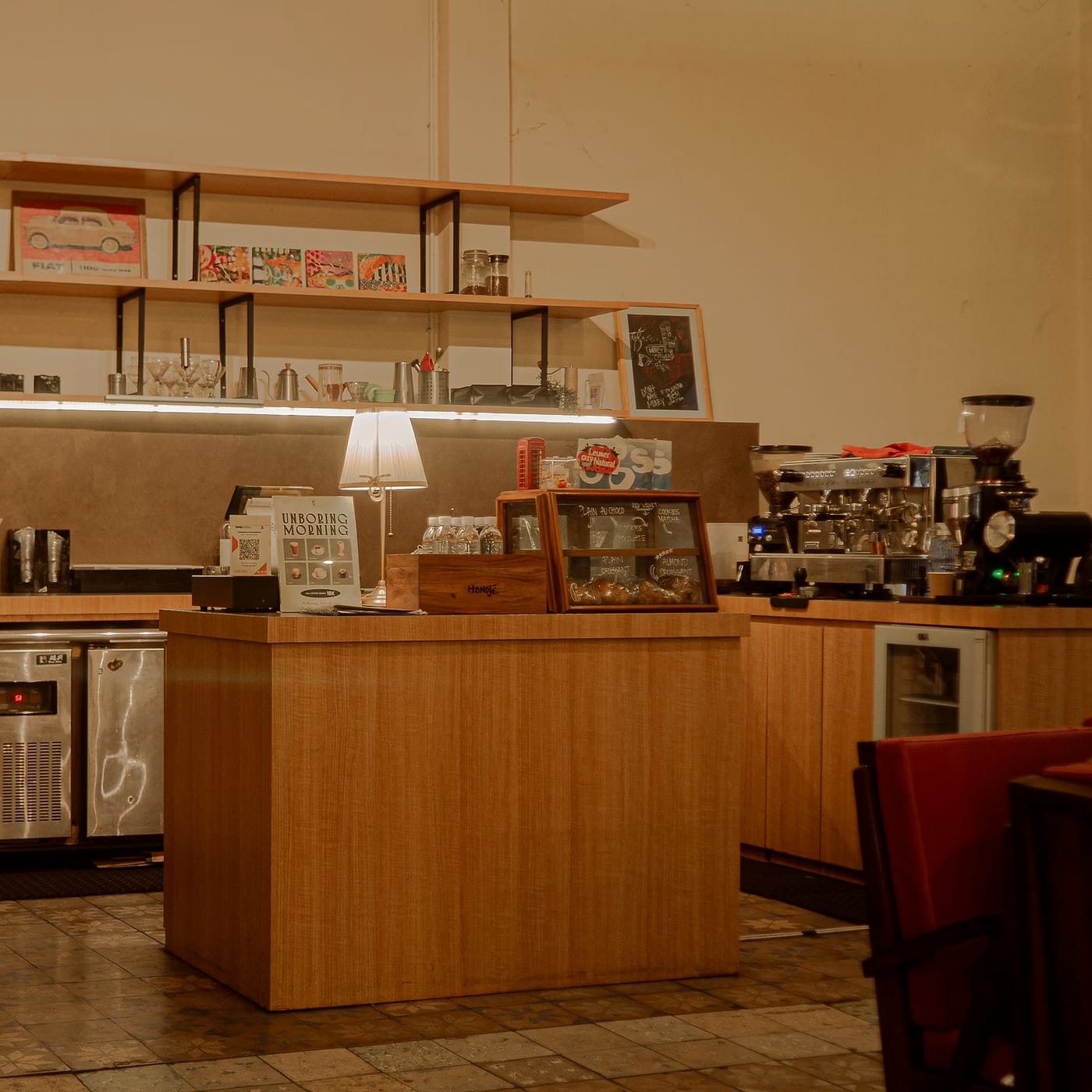 A wooden counter under shelves of cups, lit by a small lamp.